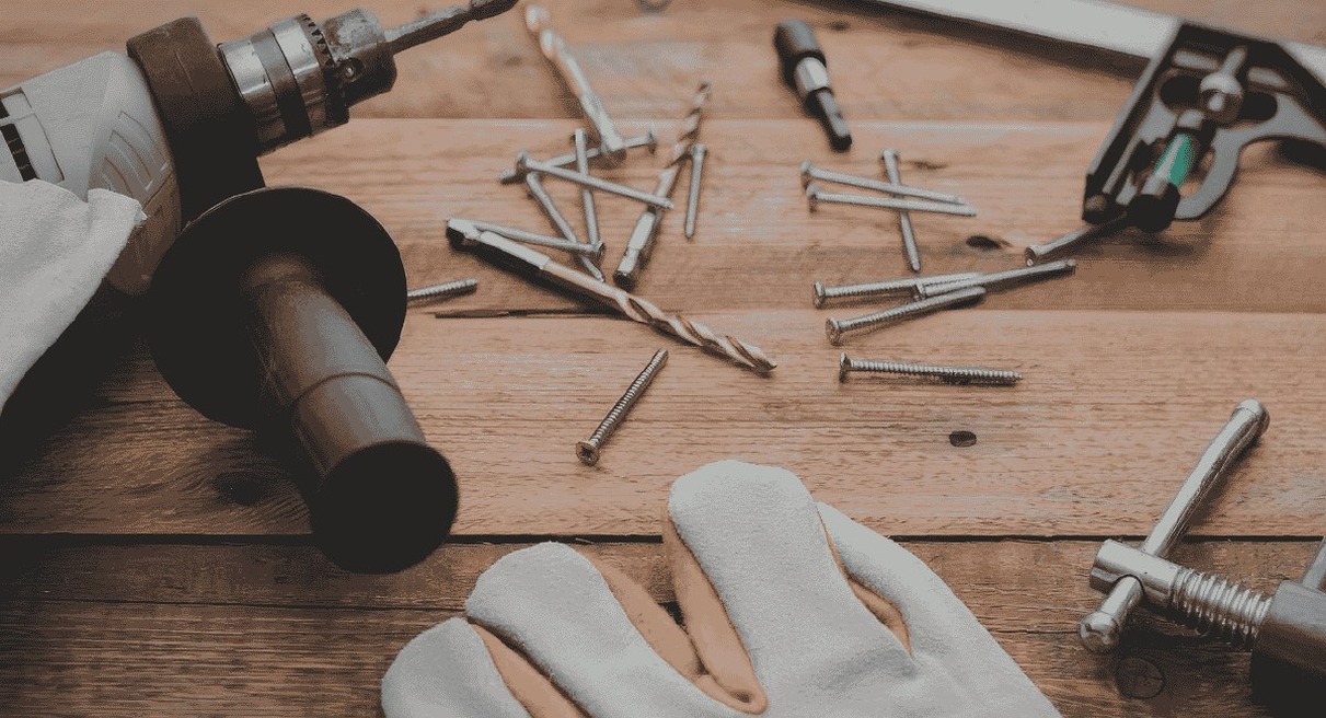 Perceuse, vis et gants de travail sur un établi de bricolage