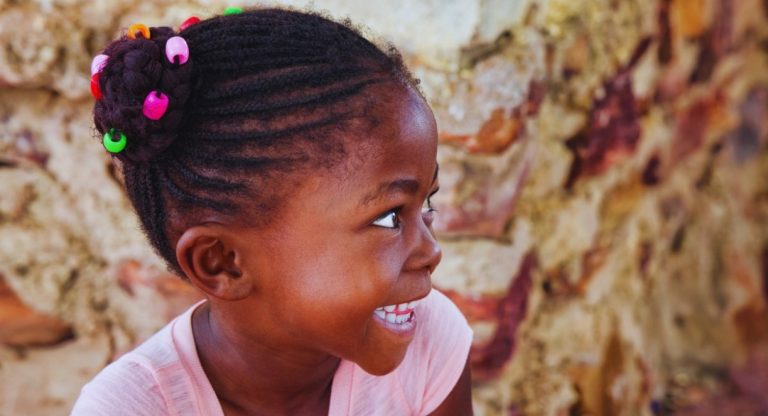 Enfant africaine souriante en tenue traditionnelle dans un village