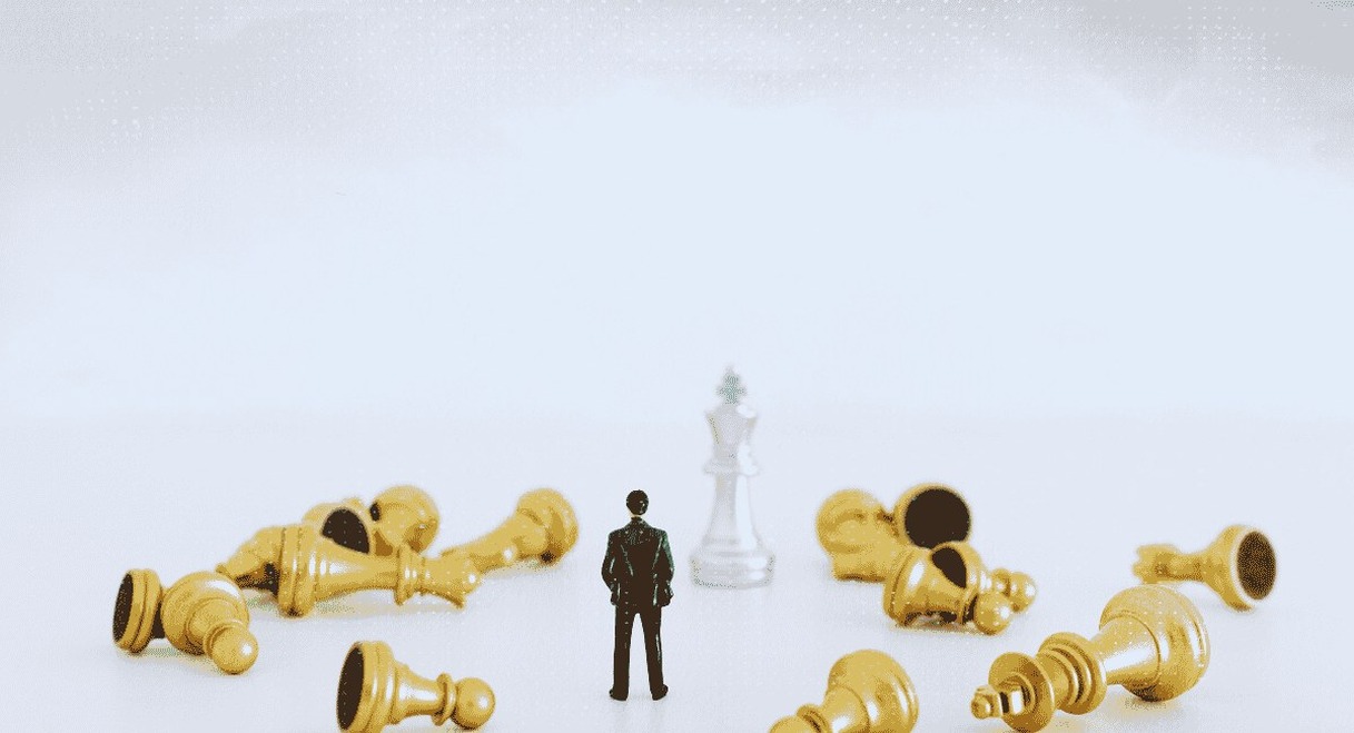 Figurine solitaire entourée de pièces d'échecs renversées sur échiquier