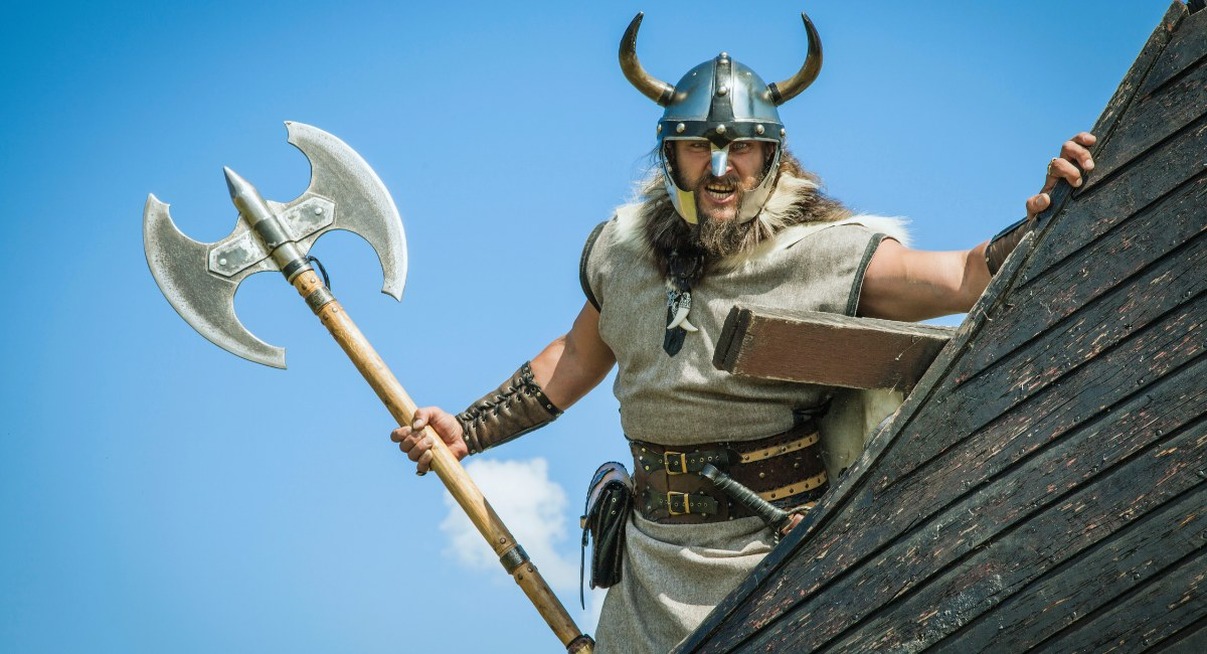Guerrier viking avec hache et casque à cornes sur un drakkar
