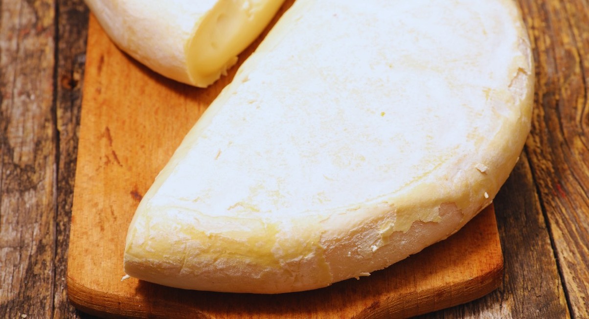 Fromage reblochon entier et coupé posé sur une planche en bois
