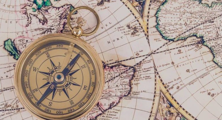 Boussole dorée vintage posée sur une carte du monde ancienne
