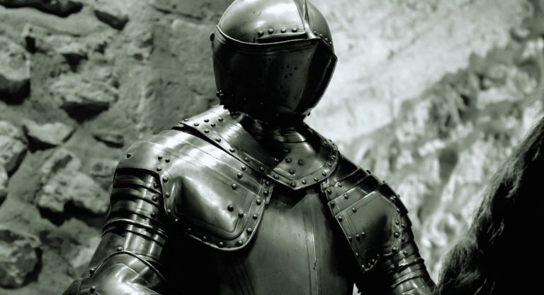 Armure de chevalier médiéval complète avec casque devant un mur en pierre