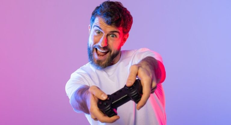 Homme souriant tenant une manette de jeu sous un éclairage néon coloré